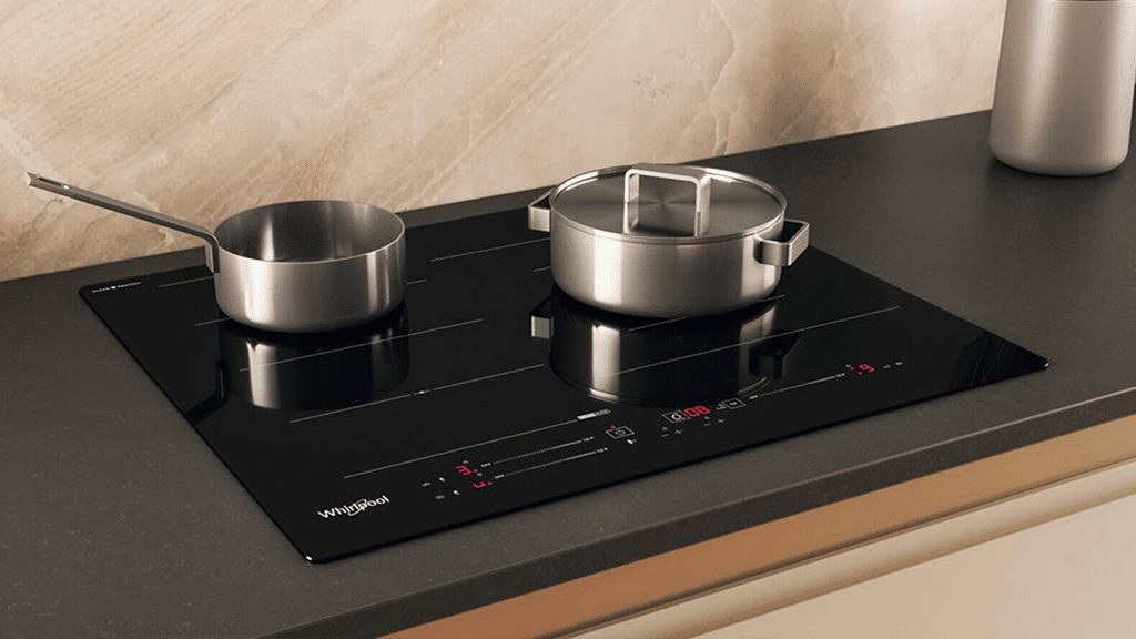Whirlpool built-in induction hob with cookware in modern kitchen